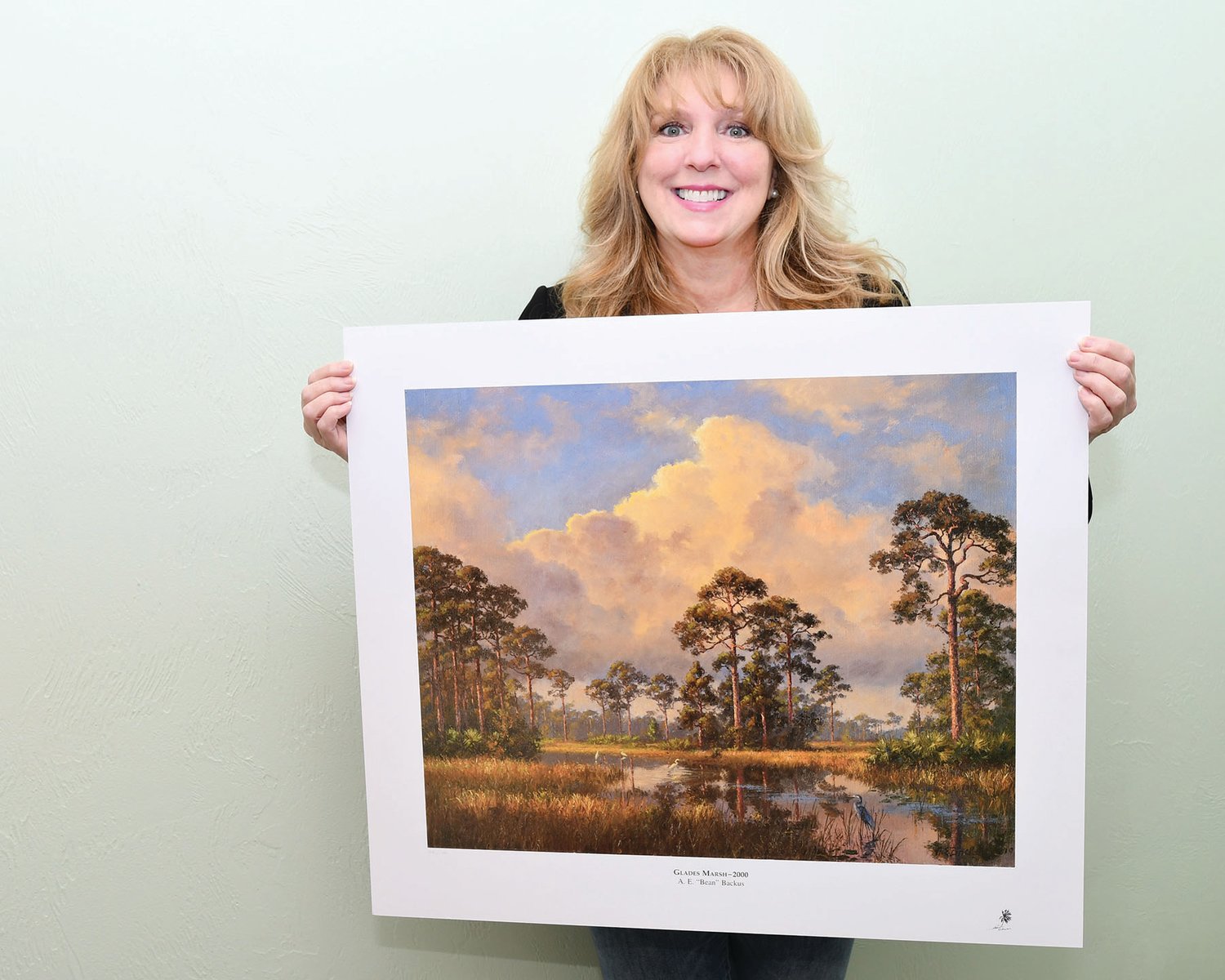 Judith Cruz, Treasure Coast Food Bank President and CEO displays a Backus print that will be up for auction.